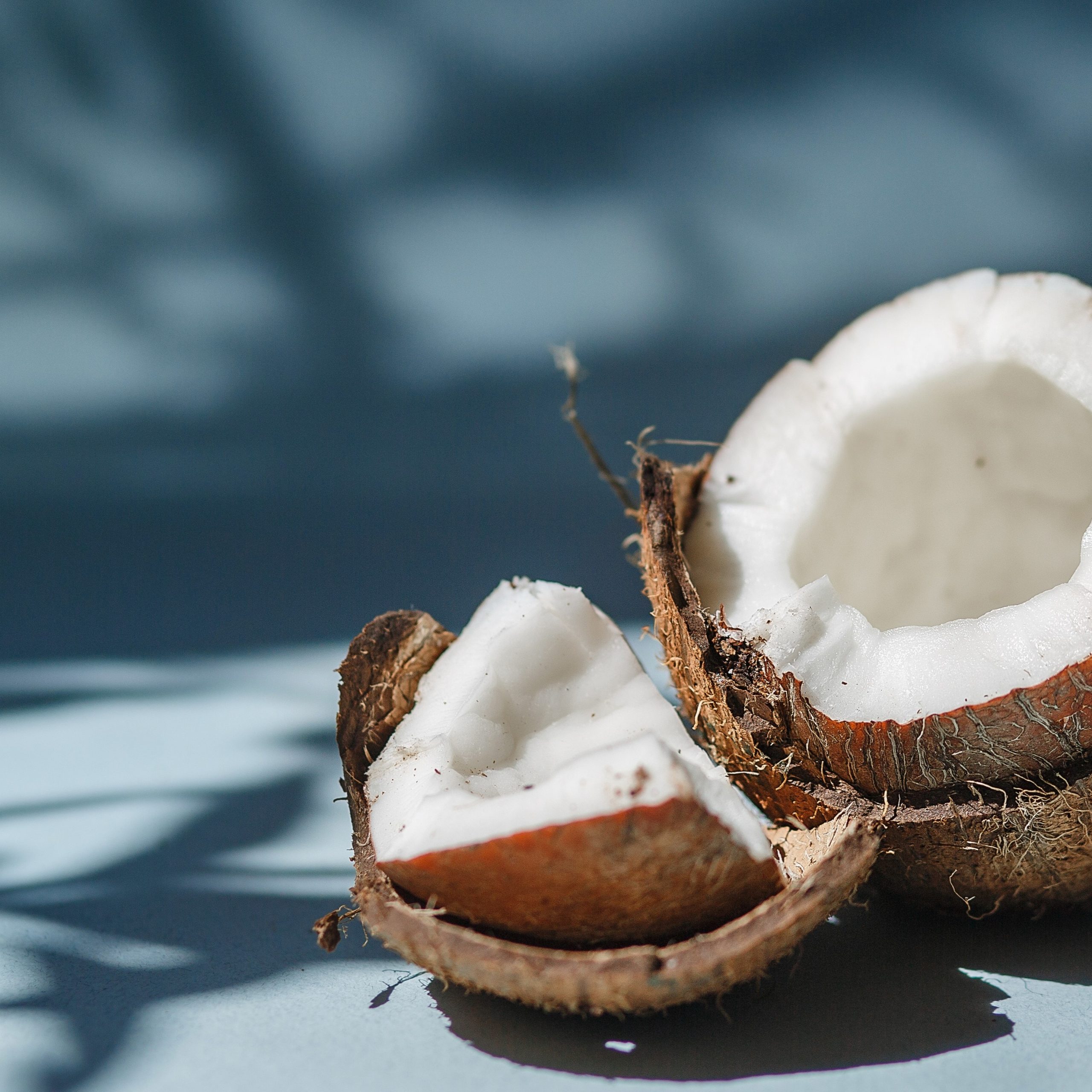 Half a coconut and pieces of coconut on a blue background.