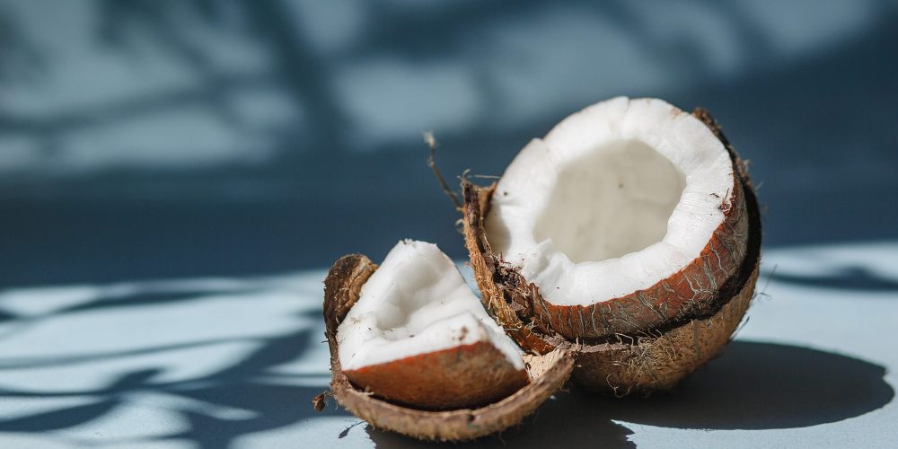 Half a coconut and pieces of coconut on a blue background.